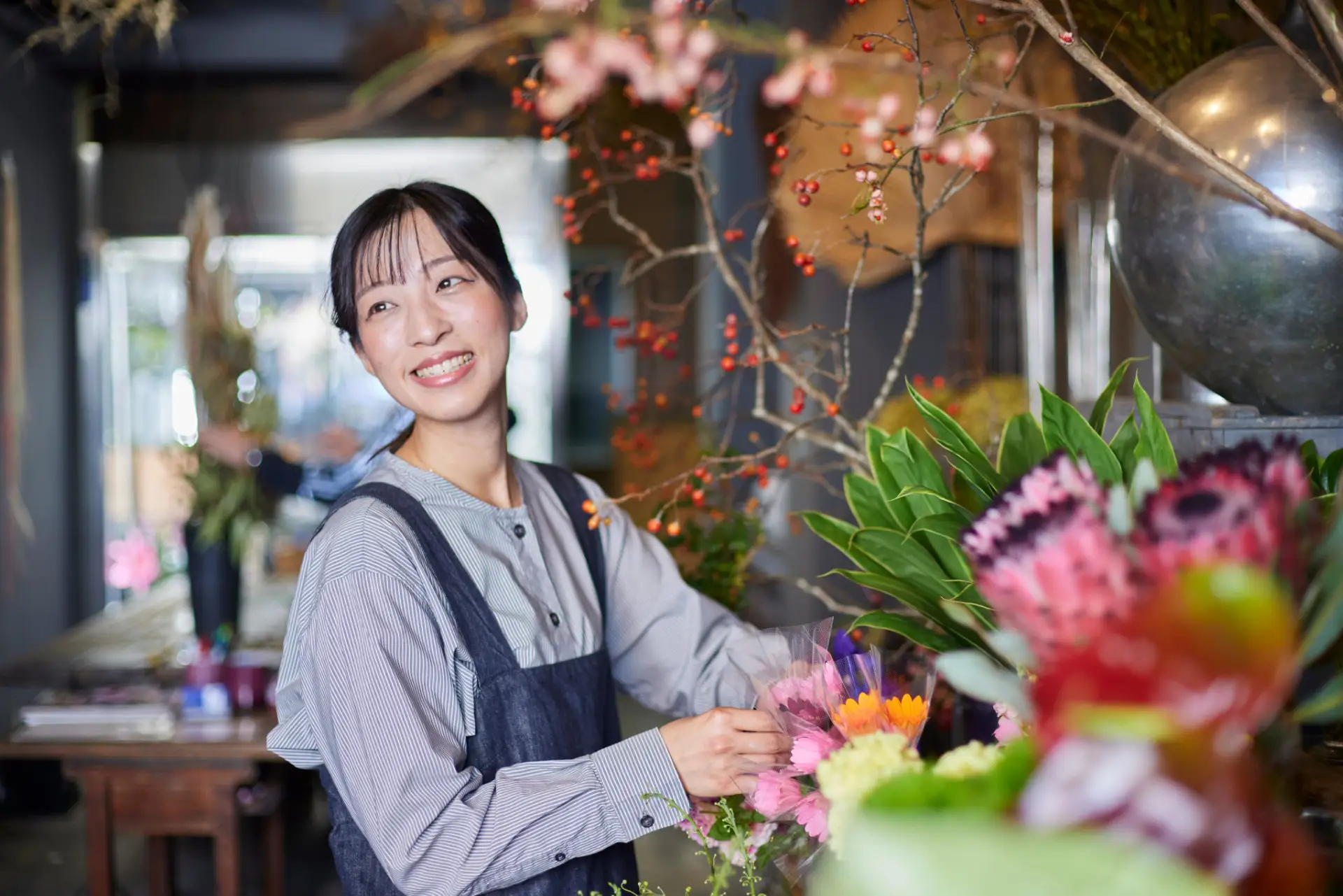 花屋の店内で、色とりどりの花に囲まれながら作業をする女性